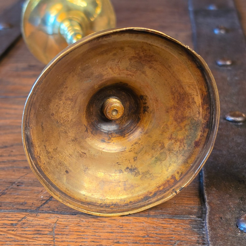 A pair of turned brass pricket candlesticks with circular drip pans and central sharp spikes on stepped round bases. View V