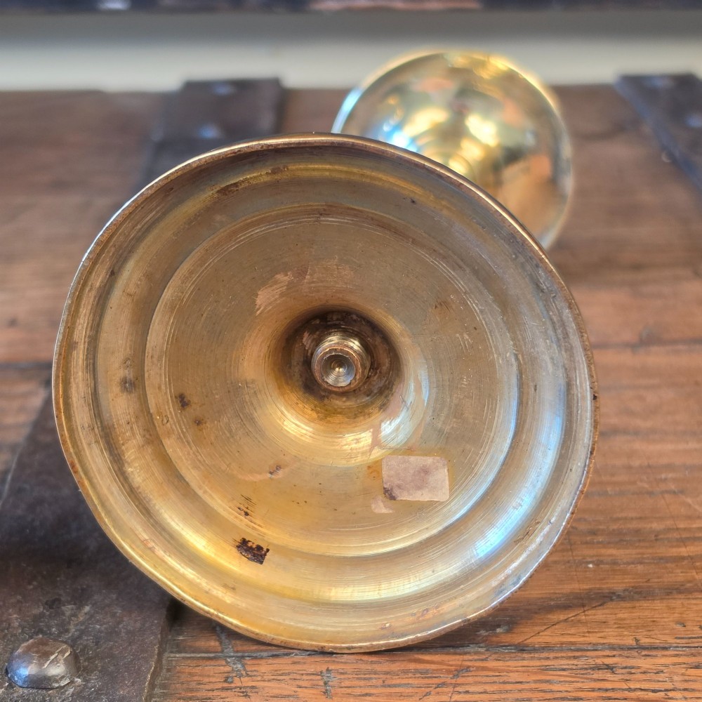 A pair of turned brass pricket candlesticks with circular drip pans and central sharp spikes on stepped round bases. View VI