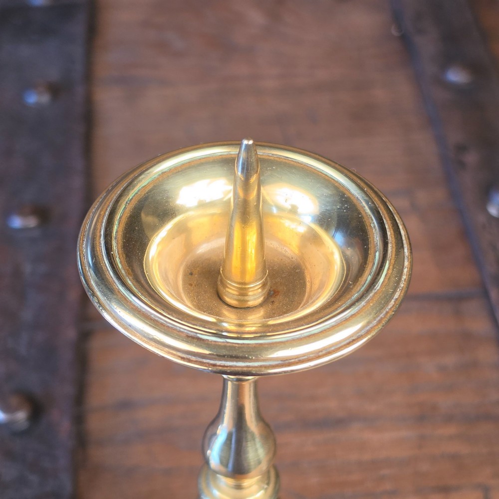 A pair of brass pricket candlesticks featuring central spikes, circular drip pans, baluster-turned stems, and stepped bases. View II