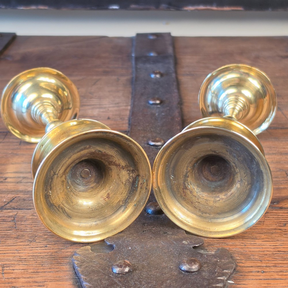 A pair of brass pricket candlesticks featuring central spikes, circular drip pans, baluster-turned stems, and stepped bases. View IV
