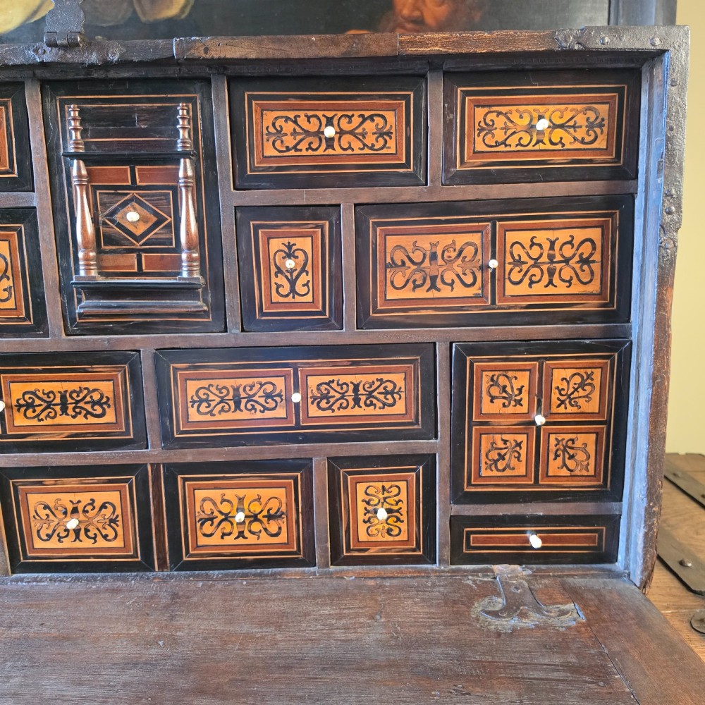 A seventeenth-century dark walnut fall-front table cabinet featuring multiple drawers decorated with intricate geometric and scrollwork wood inlays around an architectural central door. View IX