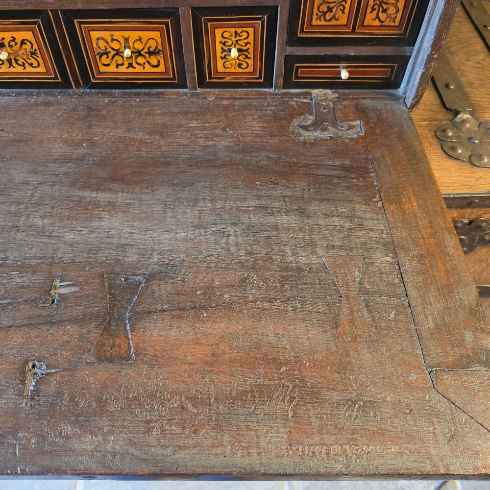 A seventeenth-century dark walnut fall-front table cabinet featuring multiple drawers decorated with intricate geometric and scrollwork wood inlays around an architectural central door. View XII