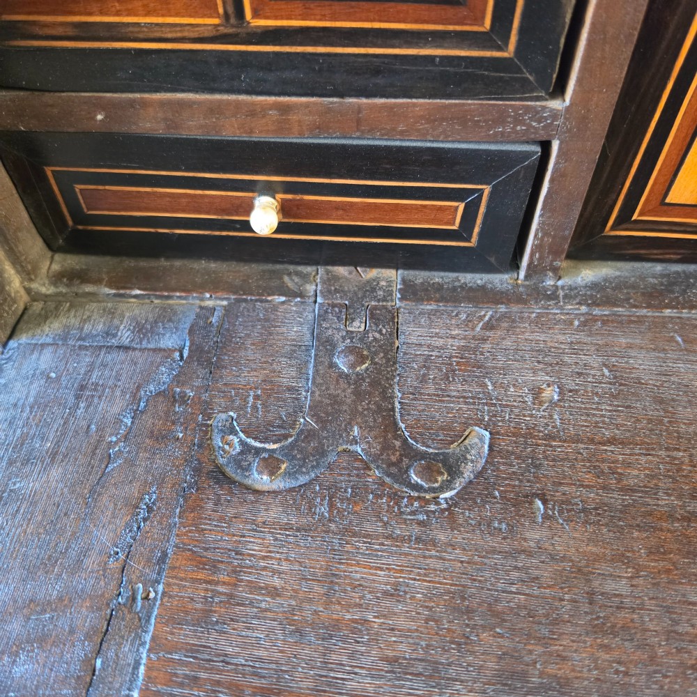 A seventeenth-century dark walnut fall-front table cabinet featuring multiple drawers decorated with intricate geometric and scrollwork wood inlays around an architectural central door. View XIII