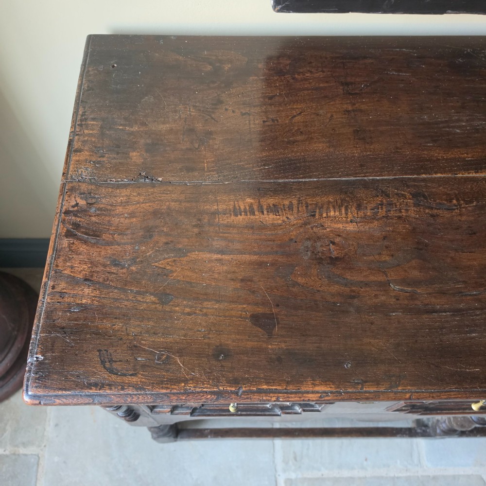 A long 17th-century dark oak dresser base featuring geometric moulded drawers, turned legs, and a shaped apron. View VIII