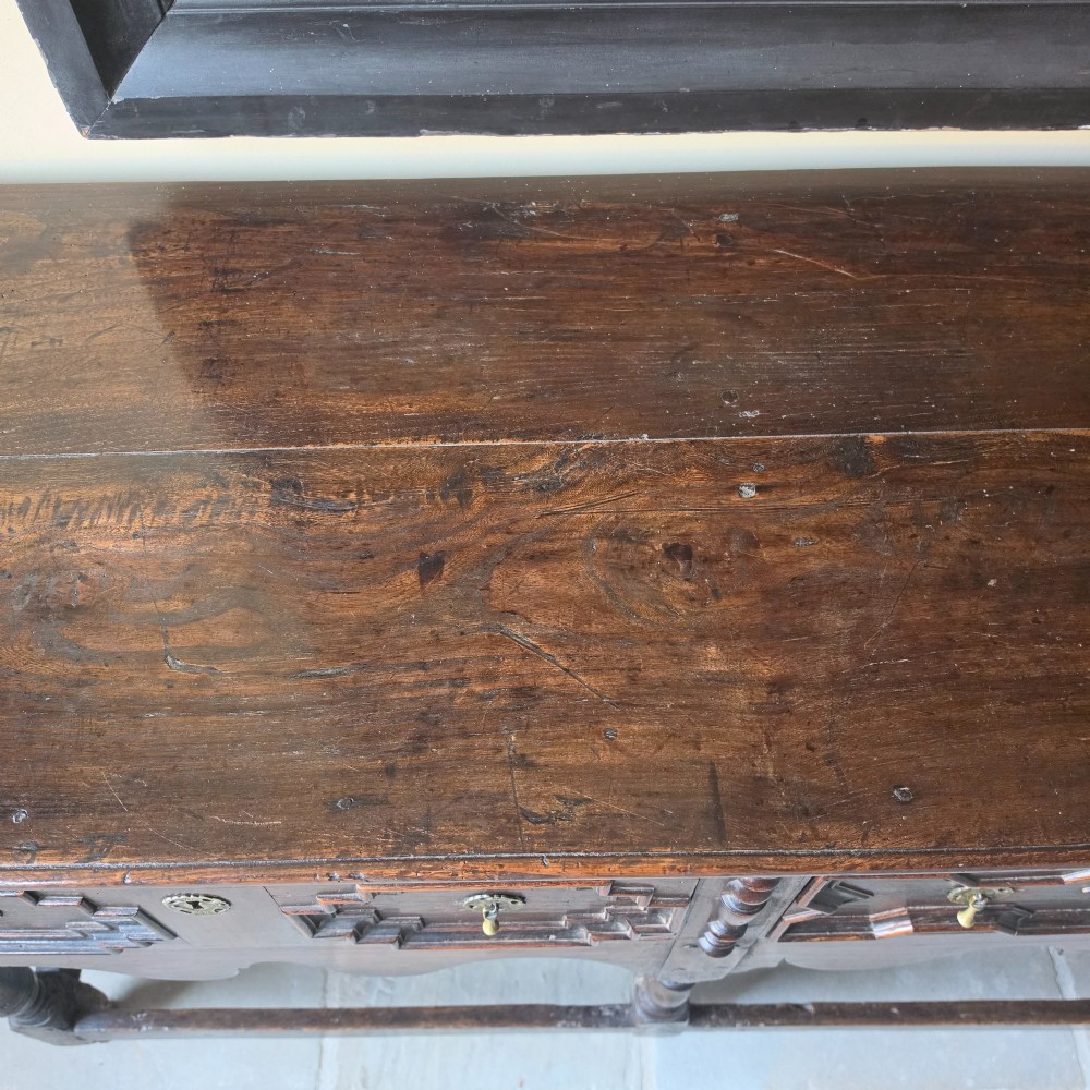 A long 17th-century dark oak dresser base featuring geometric moulded drawers, turned legs, and a shaped apron. View IX