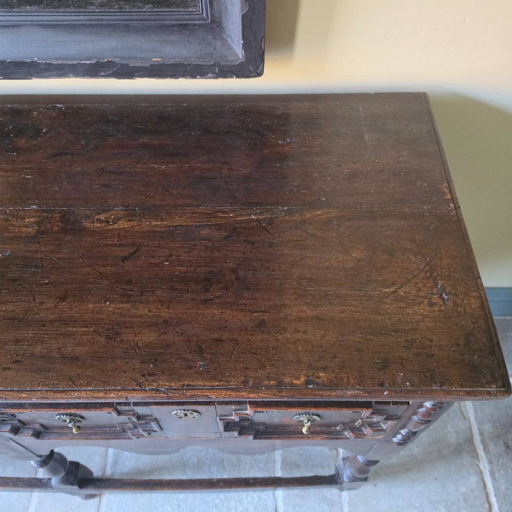A long 17th-century dark oak dresser base featuring geometric moulded drawers, turned legs, and a shaped apron. View X