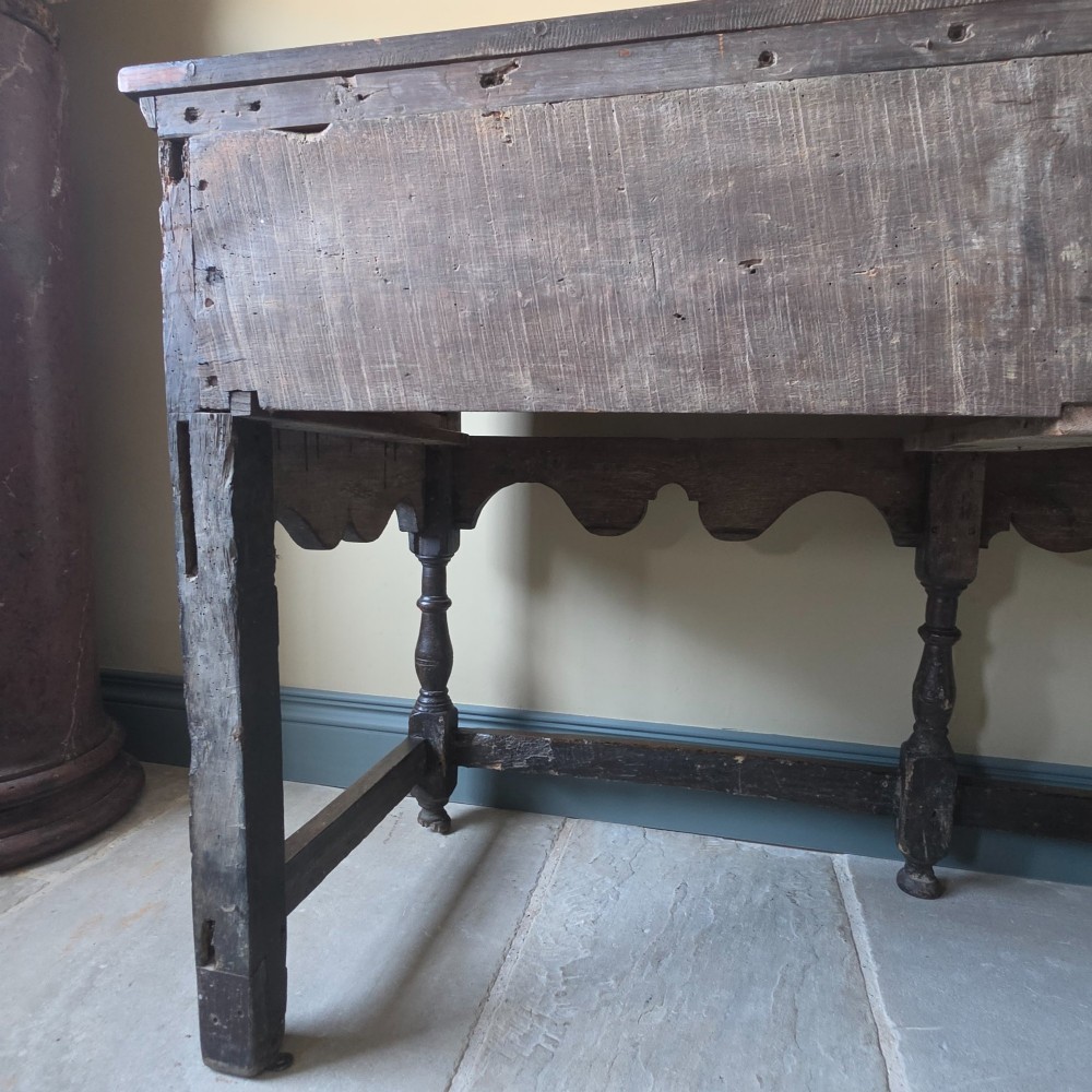 A long 17th-century dark oak dresser base featuring geometric moulded drawers, turned legs, and a shaped apron. View XV