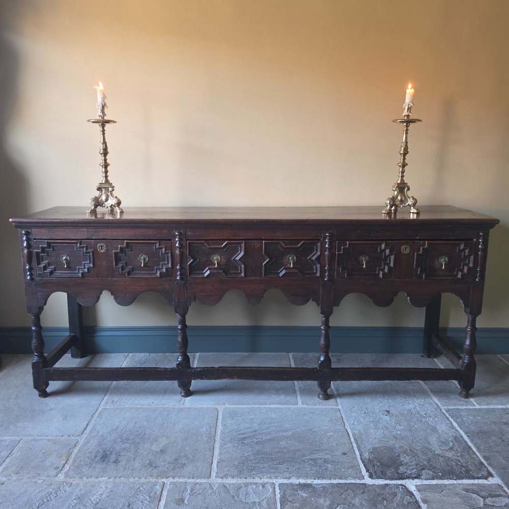 A long 17th-century dark oak dresser base featuring geometric moulded drawers, turned legs, and a shaped apron. View II