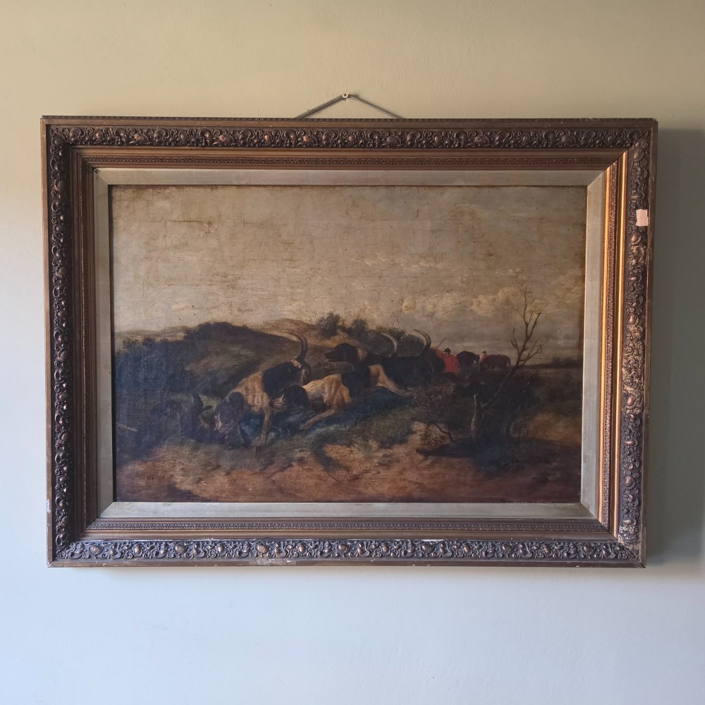 A 19th-century horizontal oil painting on canvas depicting a pack of hunting hounds in a rural landscape, set within an ornate carved gilt frame.