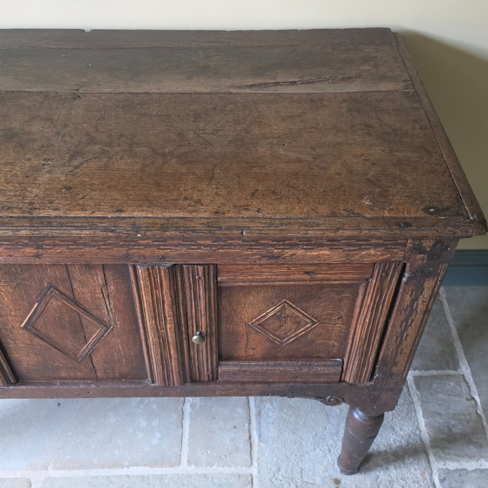 A 17th century dark oak food hutch with carved diamond lozenge doors and turned front legs. View III