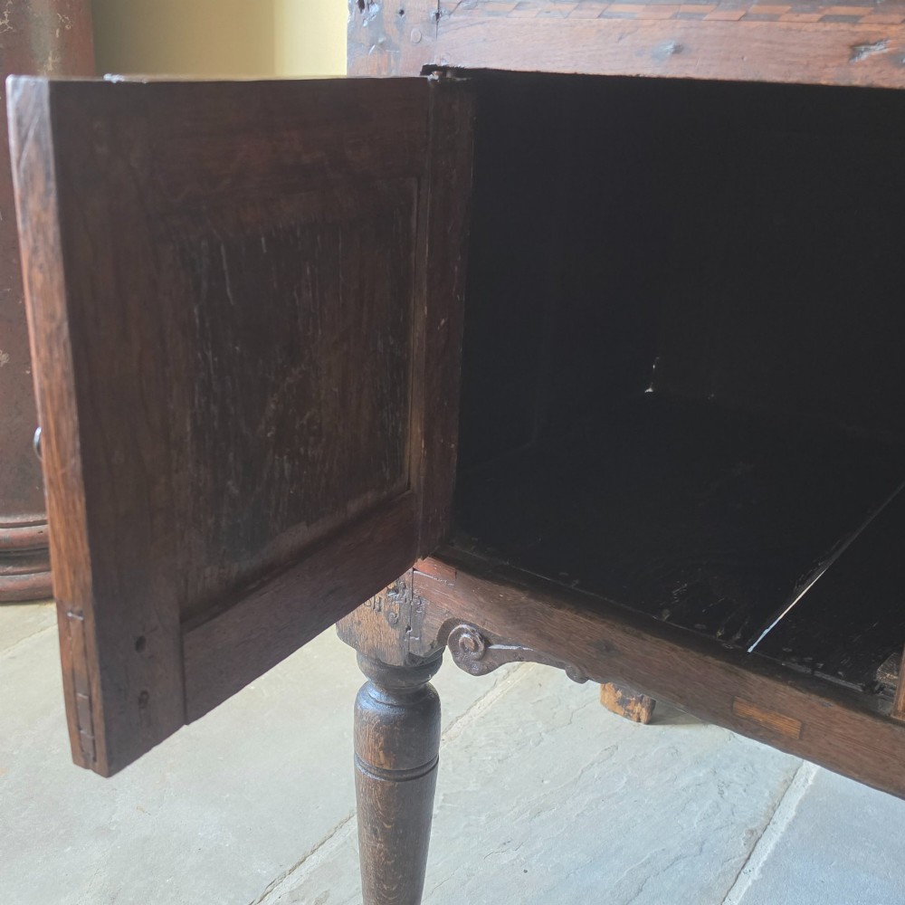 A 17th century dark oak food hutch with carved diamond lozenge doors and turned front legs. View XI