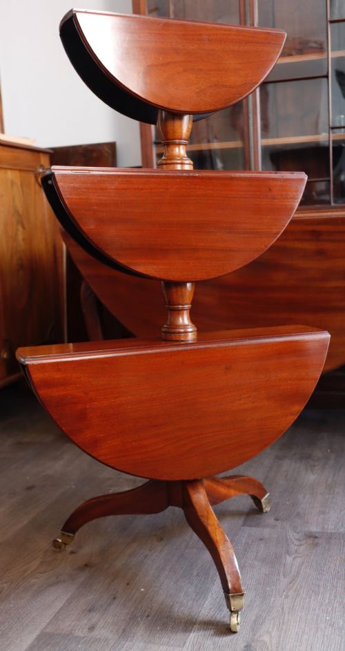 fig 1. A three-tiered mahogany dumb waiter featuring circular graduating surfaces supported by turned central columns and a tripod base on brass castors.