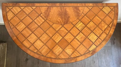 fig 1. An antique George III demilune card table in honey satinwood featuring geometric parquetry inlay and tapered legs.