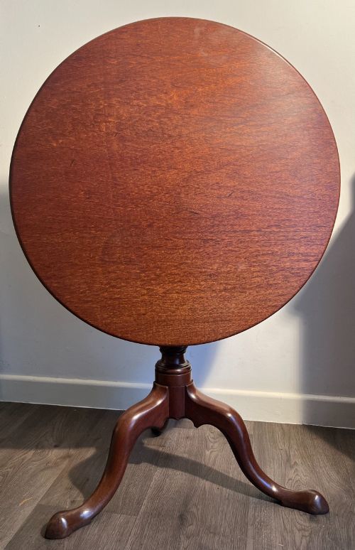 fig 2. A mahogany tilt-top tripod table shown with its top positioned vertically, revealing a turned central column and cabriole legs.