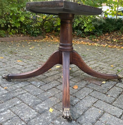 fig 1. An antique wood tilt-top dining table displaying a circular crossbanded top with inlaid border on a central pedestal base.