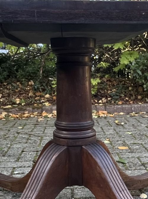 An antique wood tilt-top dining table displaying a circular crossbanded top with inlaid border on a central pedestal base. View VIII