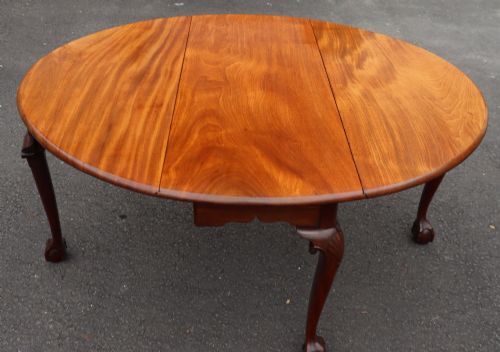fig 1. An oval mahogany drop-leaf dining table supported by carved cabriole legs ending in ball-and-claw feet.