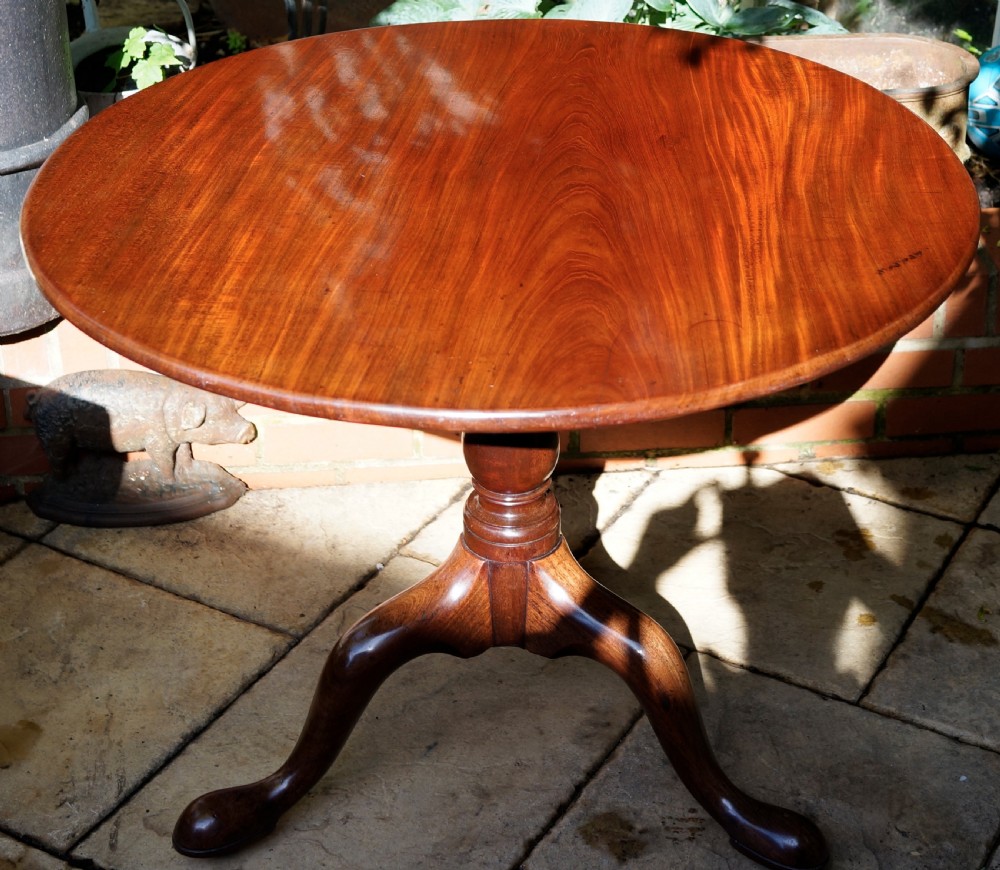 A Georgian mahogany tripod table featuring a circular top, turned central column, and three cabriole legs ending in pad feet.