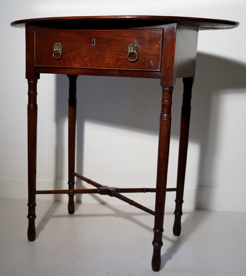 Oval mahogany table supported on four turned tapering legs braced by turned under frame retaining original lion mask