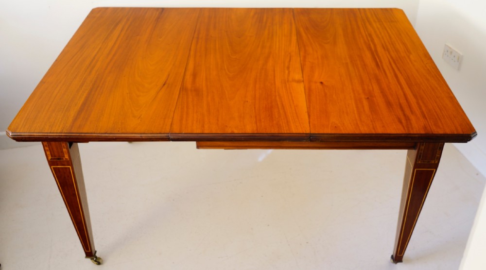 1900s extending wind-out mahogany inlaid dining table on square tapering legs.
