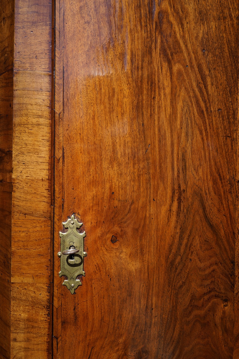 A George II hanging corner cupboard constructed from figured walnut veneer featuring a single door and a brass escutcheon plate. View II