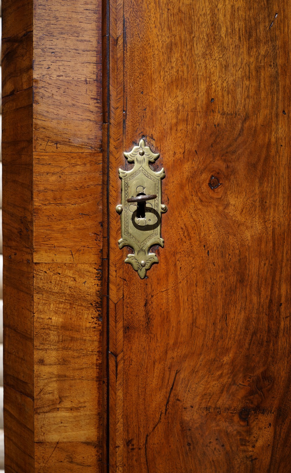 A George II hanging corner cupboard constructed from figured walnut veneer featuring a single door and a brass escutcheon plate. View V