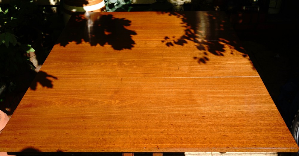 A George III mahogany drop leaf dining table with six tapered legs terminating in pad feet. View IV