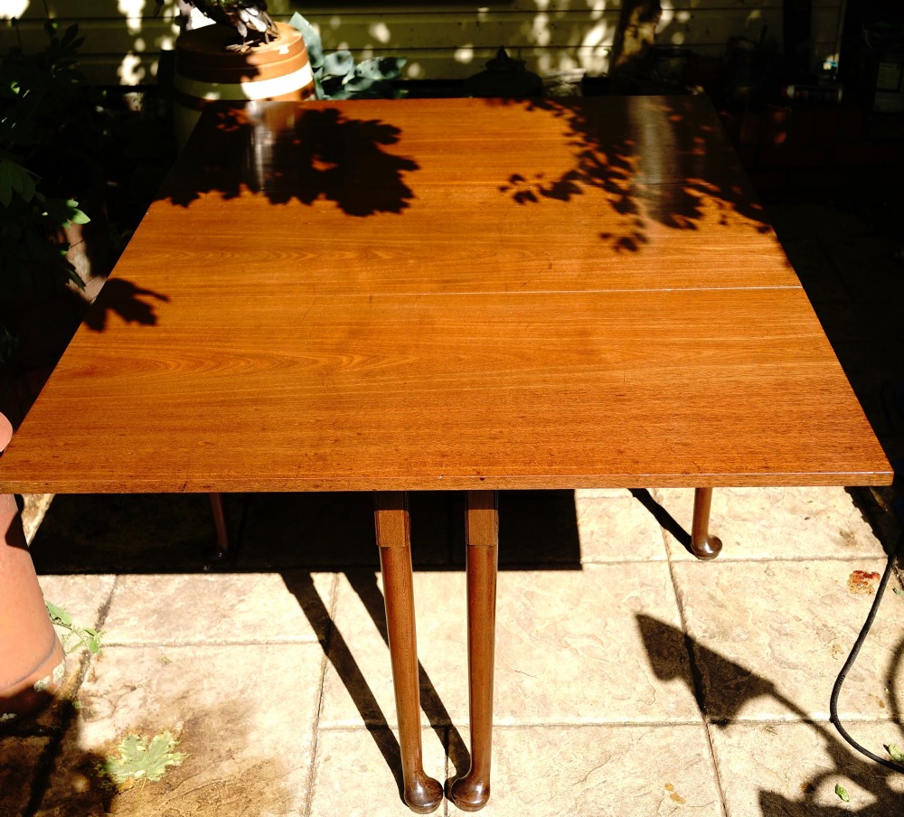 A George III mahogany drop leaf dining table with six tapered legs terminating in pad feet.