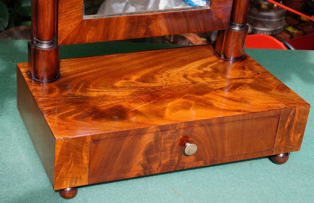 A Victorian mahogany swing dressing mirror featuring a pediment top decorated with a brass mount, side columns, and a single drawer base. View V