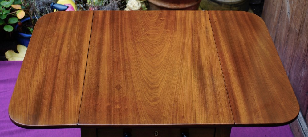 A Regency period mahogany side table featuring two drop flaps, a single drawer with two dark turned knobs, and four ring-turned legs on brass castors. View VI