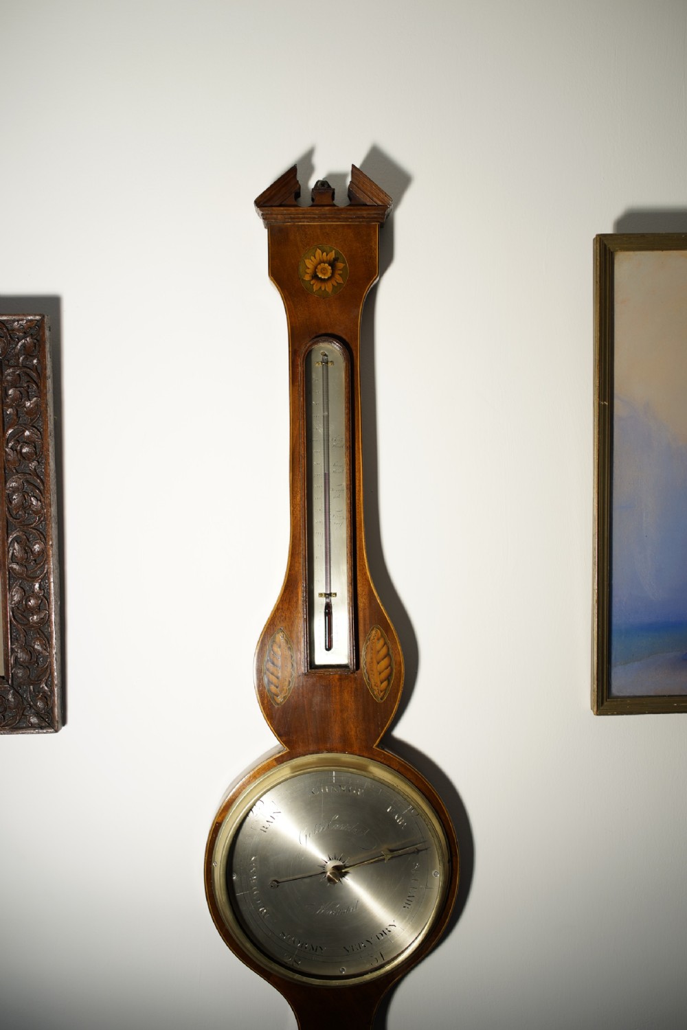 An antique 1830s William IV mahogany banjo barometer featuring shell marquetry inlays, a central thermometer, and a round silvered dial. View V