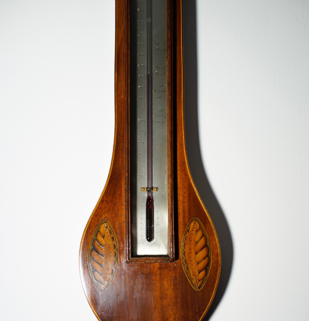 An antique 1830s William IV mahogany banjo barometer featuring shell marquetry inlays, a central thermometer, and a round silvered dial. View VI