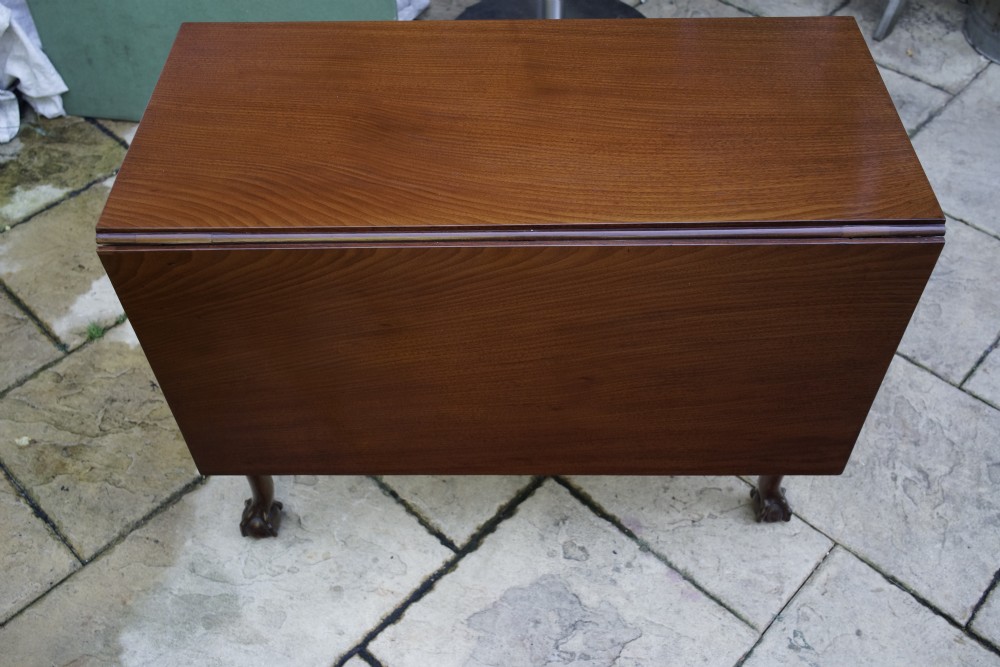 An eighteenth-century mahogany drop leaf table with a polished rectangular top, turned legs, and hand-carved claw and ball feet.