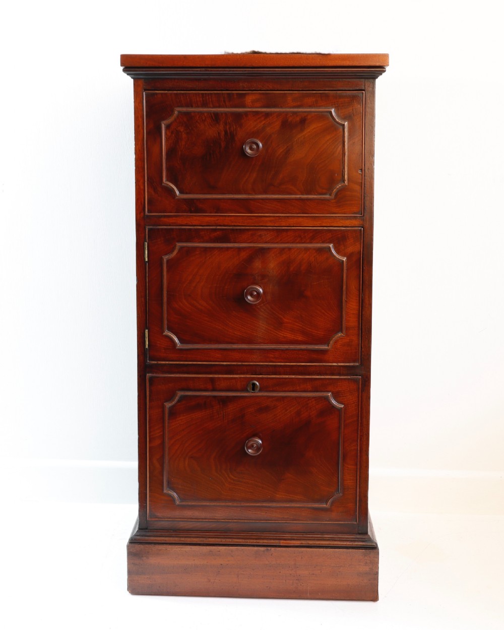 A tall antique flame mahogany cellarette cabinet styled as a chest with three faux drawer fronts, turned wooden knobs, and a solid plinth base. View II