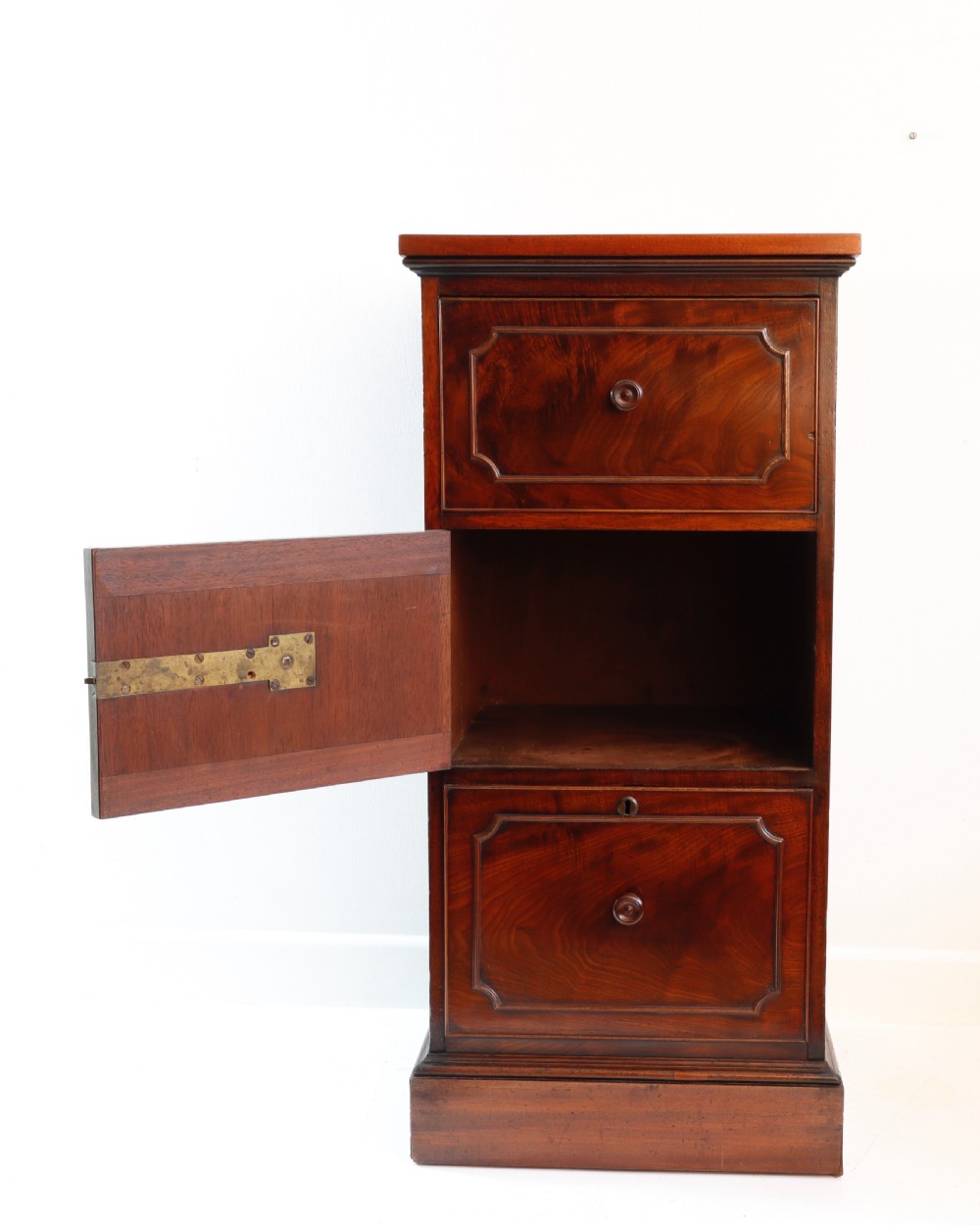 A tall antique flame mahogany cellarette cabinet styled as a chest with three faux drawer fronts, turned wooden knobs, and a solid plinth base. View VI