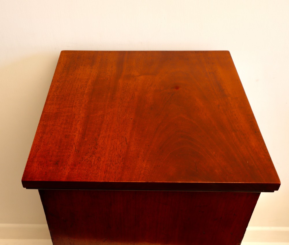 A tall antique flame mahogany cellarette cabinet styled as a chest with three faux drawer fronts, turned wooden knobs, and a solid plinth base. View IX