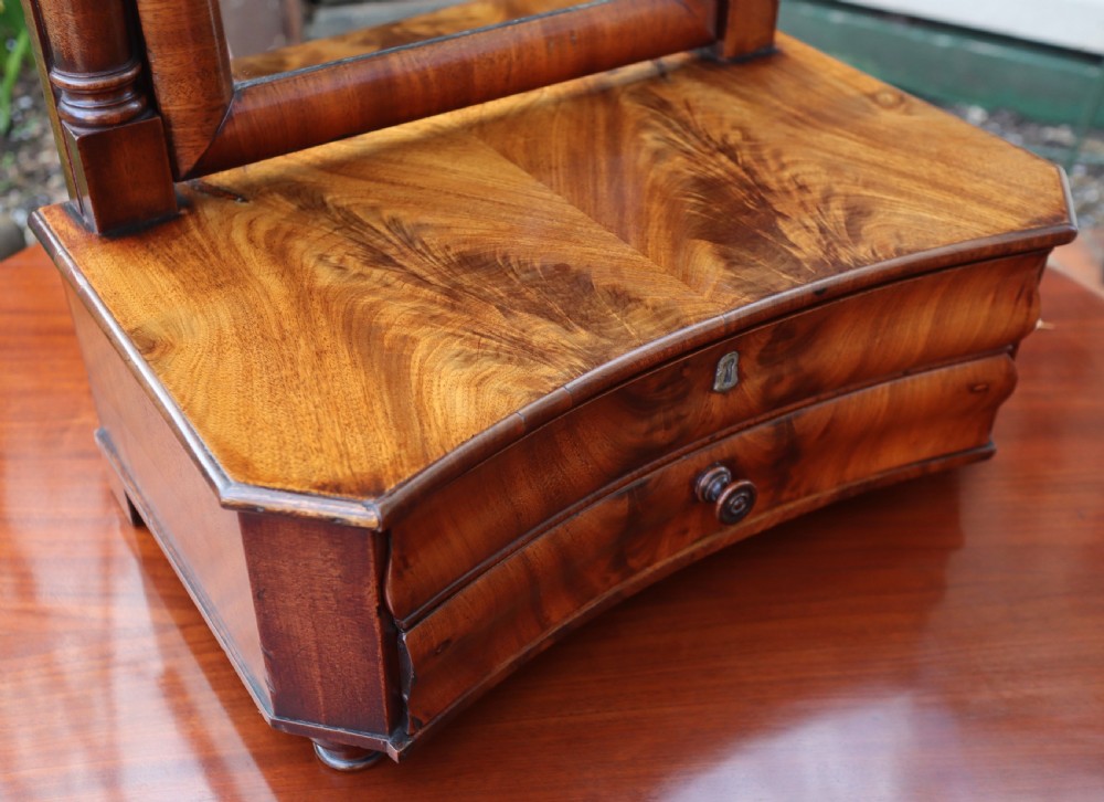 An antique mahogany tabletop toilet mirror featuring an adjustable swivel glass frame supported by turned columns over a two-drawer serpentine base. View V