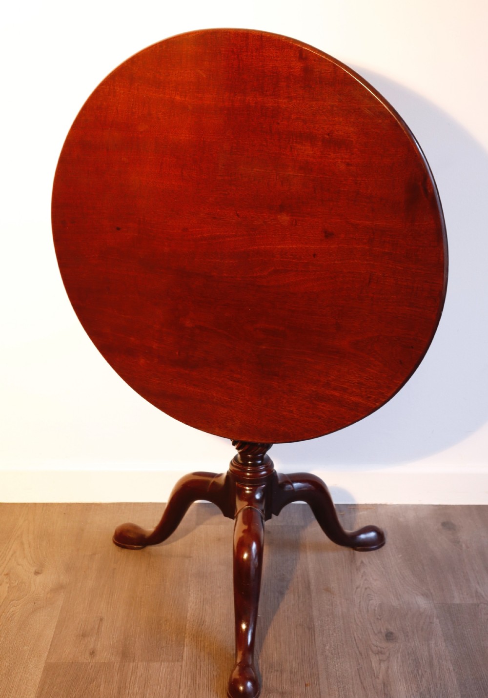 A circular mahogany tilt-top table shown with its surface flipped vertically, resting on a turned column with three pad-foot cabriole legs. View II