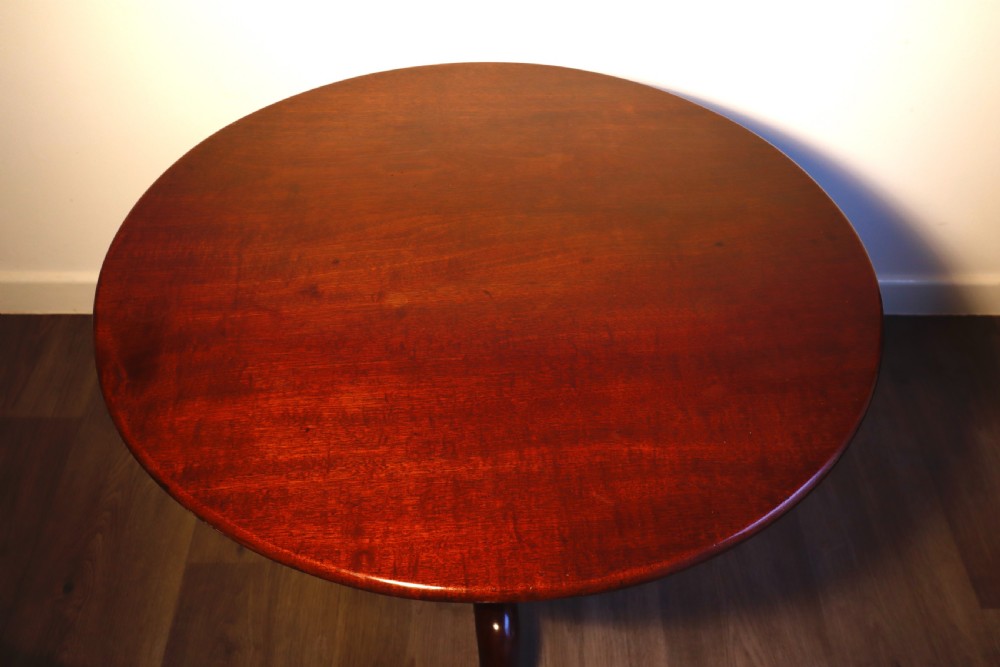 A circular mahogany tilt-top table shown with its surface flipped vertically, resting on a turned column with three pad-foot cabriole legs. View IV