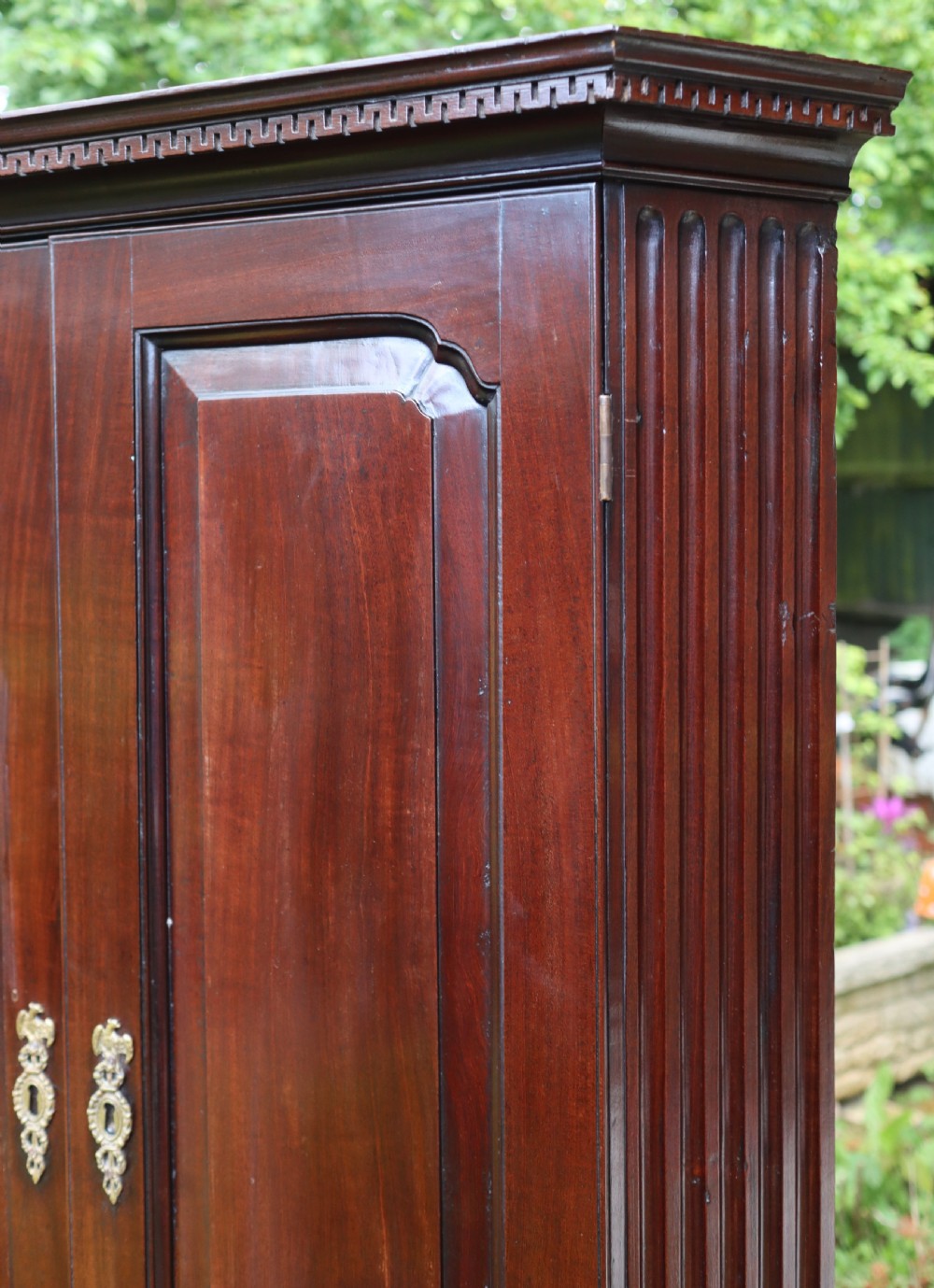 An 18th-century Georgian mahogany two-door corner cupboard featuring fluted pilasters, dentil moulding along the top cornice, and shaped fielded panel doors with brass escutcheons. View III