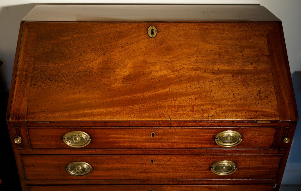 An antique Georgian mahogany bureau featuring a slant-front writing slope over four graduated drawers with brass oval handles. View III