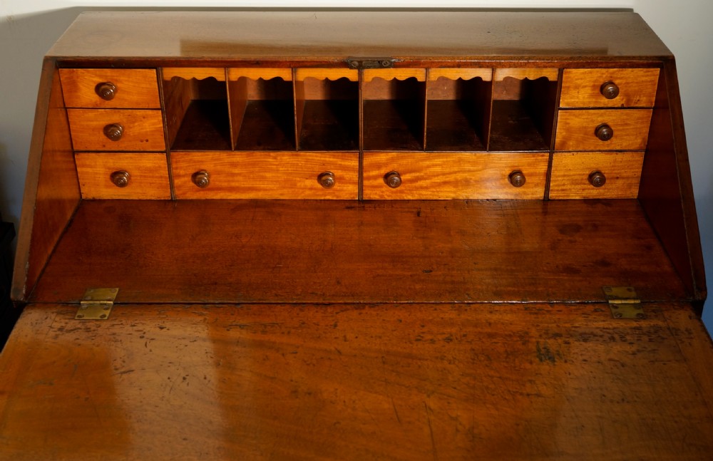 An antique Georgian mahogany bureau featuring a slant-front writing slope over four graduated drawers with brass oval handles. View V
