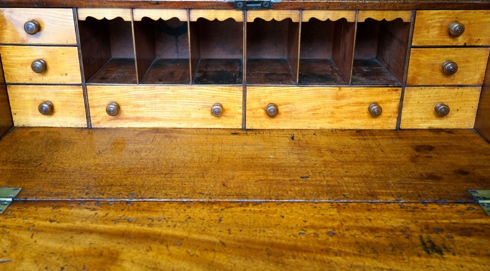 An antique Georgian mahogany bureau featuring a slant-front writing slope over four graduated drawers with brass oval handles. View VI