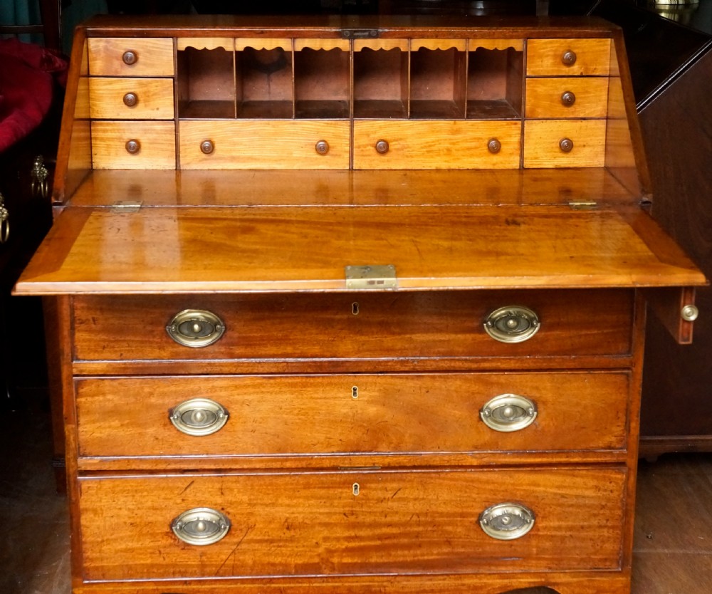 An antique Georgian mahogany bureau featuring a slant-front writing slope over four graduated drawers with brass oval handles. View VII