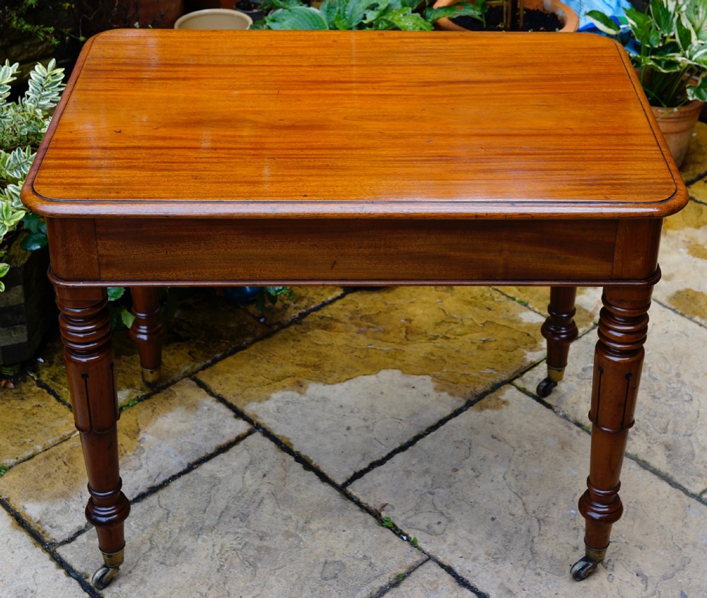 A rectangular mahogany centre table featuring a polished top surface, turned legs, and brass castors. View II