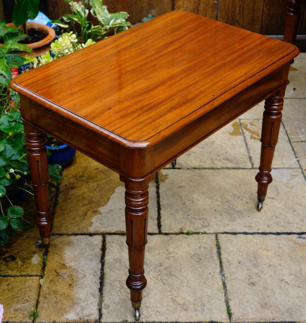 A rectangular mahogany centre table featuring a polished top surface, turned legs, and brass castors. View III