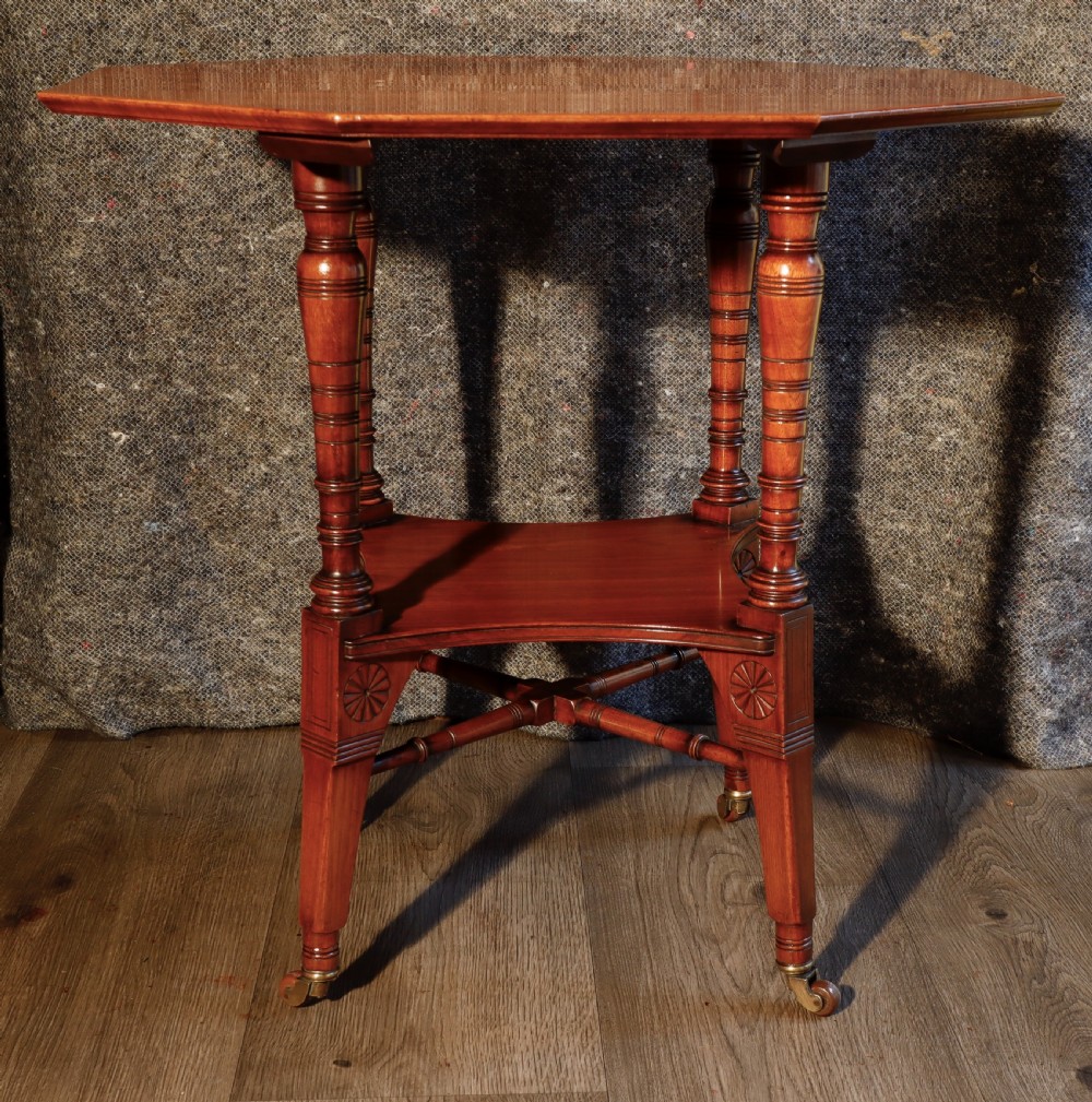 An antique octagonal walnut occasional table featuring a lower tier shelf, turned legs, rosette carving, cross-stick bracing, and brass castors. View II