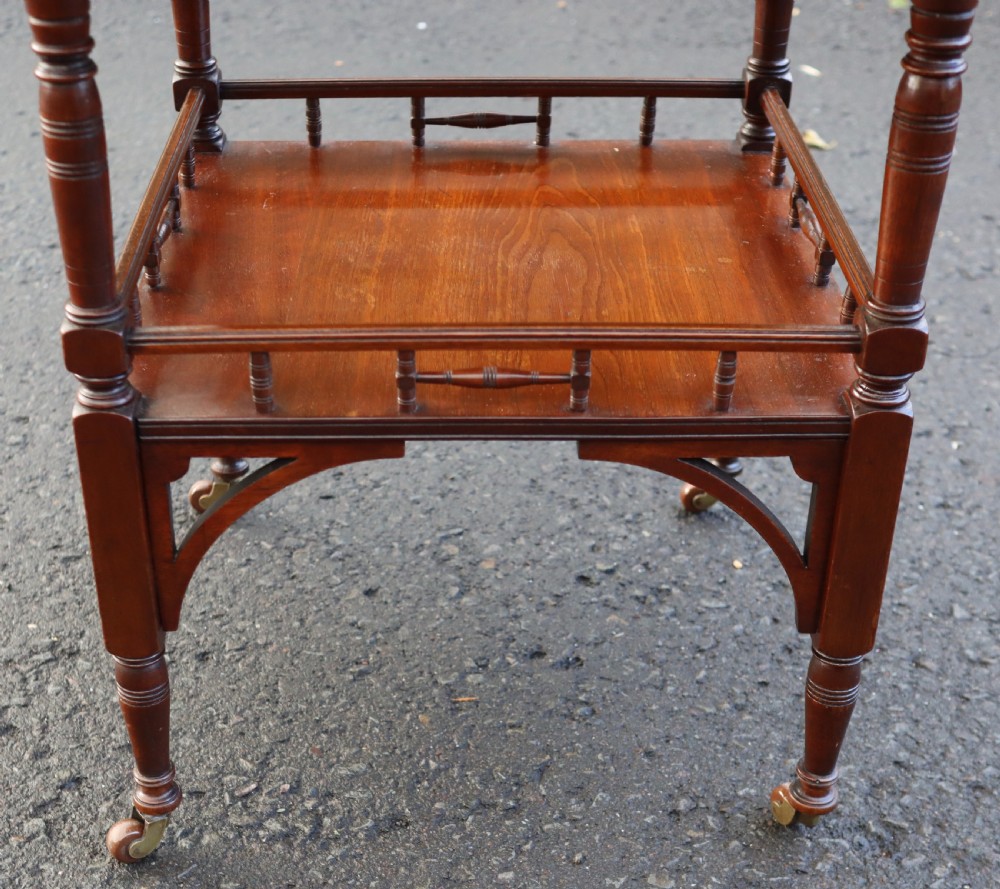 A late Victorian octagonal walnut occasional table featuring a secondary lower tier with a spindle gallery, turned legs, and brass castors. View II