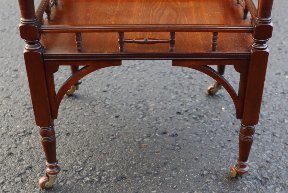 A late Victorian octagonal walnut occasional table featuring a secondary lower tier with a spindle gallery, turned legs, and brass castors. View III