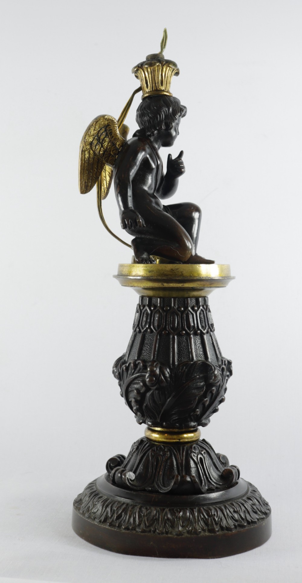 An antique French table lamp base featuring a dark patinated bronze figure of a winged cherub atop an ornate cast pedestal with gilded accents. View VI